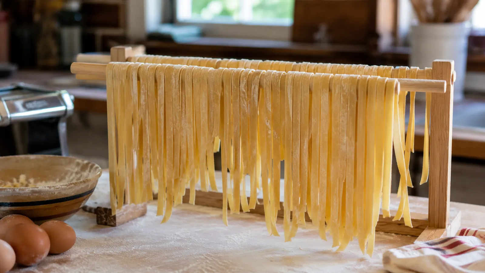 Fresh fettuccine noodles drying on a wooden rack after being cut on the Marcato Atlas pasta cutter attachment