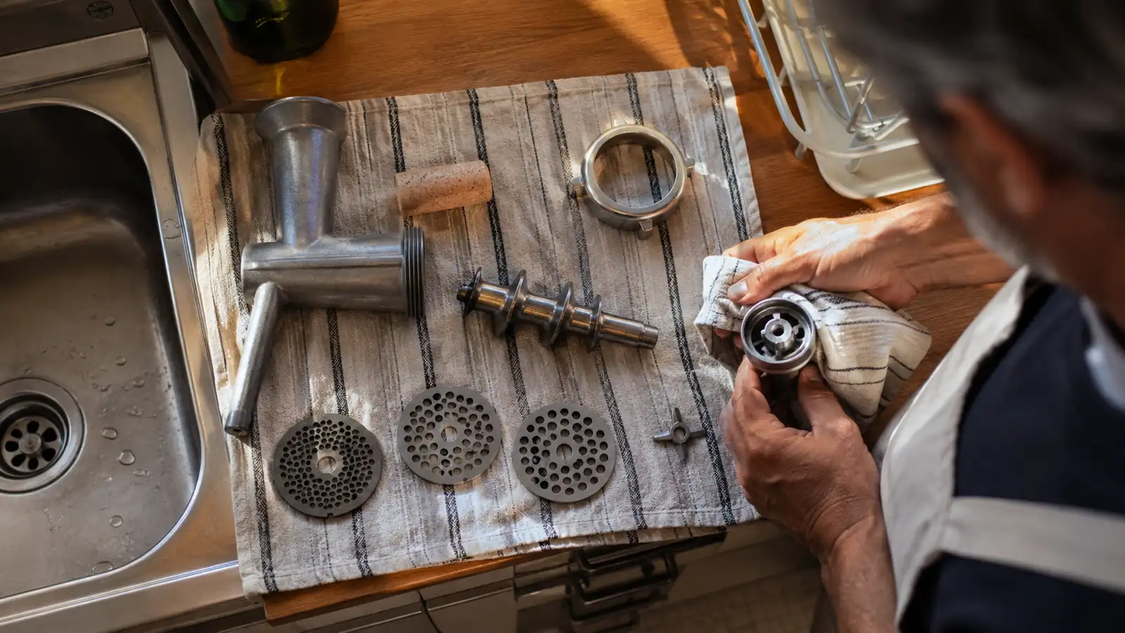 The disassembled grinder parts laid out on a towel next to the sink for hand washing